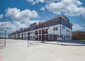 Thumbnail 7 of 7 - Gated apartment community entrance with modern townhomes at The Aurea Apartments, Houston