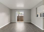 Thumbnail 26 of 31 - an empty living room with wood flooring and a door to a balcony