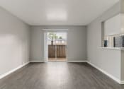 Thumbnail 29 of 31 - an empty living room with wood flooring and a door to a balcony