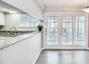 Thumbnail 13 of 15 - A kitchen with a marble countertop and white cabinets.