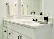 Thumbnail 28 of 31 - A white bathroom vanity with a mirror and lights above it.