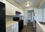 Thumbnail 20 of 31 - a kitchen with white cabinets and black appliances  at The Alara, Houston, TX