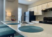 Thumbnail 18 of 31 - a kitchen with white cabinets and black appliances  at The Alara, Houston