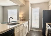 Thumbnail 17 of 31 - a kitchen with white cabinets and black appliances  at The Alara, Houston, TX, 77060