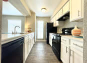 Thumbnail 12 of 31 - a kitchen with white cabinets and black appliances  at The Alara, Houston, TX, 77060