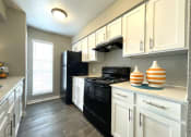 Thumbnail 10 of 31 - a kitchen with white cabinets and black appliances  at The Alara, Houston, TX