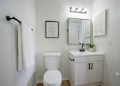 Thumbnail 25 of 27 - A white toilet sits next to a white sink in a small bathroom.