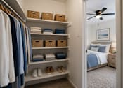 Thumbnail 22 of 27 - A bedroom with a bed, a dresser, a closet with clothes and shoes.