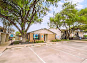 Thumbnail 7 of 31 - A parking lot in front of a building with a tree in the foreground.