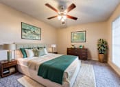 Thumbnail 1 of 5 - A bedroom with a large bed and a ceiling fan.