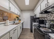 Thumbnail 3 of 5 - A kitchen with a black stove top oven and a white counter top.