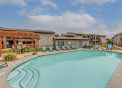 Thumbnail 5 of 5 - A swimming pool surrounded by lounge chairs and buildings.