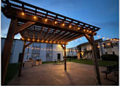 Thumbnail 5 of 27 - A wooden pergola with string lights is in the foreground of a residential area.