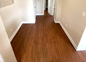 Thumbnail 7 of 13 - A long hallway with wood floors and white walls.