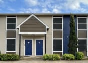 Thumbnail 3 of 16 - a building with two blue doors and a tree in front of it