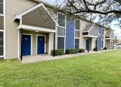 Thumbnail 4 of 16 - a row of townhomes with blue doors and green grass