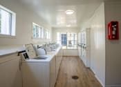 Thumbnail 12 of 27 - A laundry room with a washer and dryer and a red fire extinguisher on the wall.