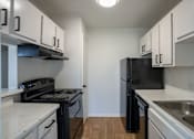 Thumbnail 13 of 27 - A kitchen with black appliances and white cabinets.