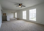 Thumbnail 17 of 27 - A room with a ceiling fan and carpeted floor.