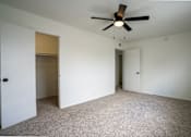 Thumbnail 23 of 27 - A room with a ceiling fan and carpeted floor.