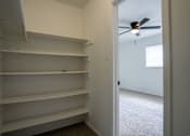 Thumbnail 21 of 27 - Empty white shelves in a room with a ceiling fan.