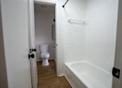 Thumbnail 26 of 27 - A white bathroom with a toilet and a bathtub.