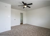 Thumbnail 19 of 27 - A room with a ceiling fan and carpeted floor.
