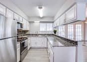 Thumbnail 7 of 15 - A kitchen with white cabinets and a granite countertop.