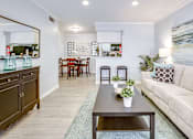 Thumbnail 4 of 12 - A living room with a couch, coffee table, and a dining table.
