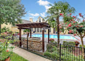 Thumbnail 1 of 12 - A pool area with a black fence and a gazebo.