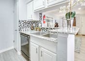 Thumbnail 3 of 12 - A kitchen with a white counter top and a sink.