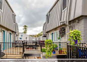 Thumbnail 15 of 15 - A view of a courtyard between two buildings with a metal fence and a small tree in the middle.