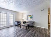 Thumbnail 9 of 10 - A living room with a grey couch and a painting on the wall.