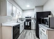 Thumbnail 2 of 10 - A kitchen with black appliances and white cabinets.