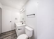 Thumbnail 25 of 31 - A white toilet sits next to a sink in a small bathroom.