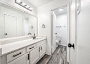 Thumbnail 26 of 31 - A bathroom with a white sink vanity and a white toilet.