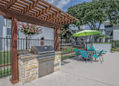 Thumbnail 4 of 14 - A wooden pergola with a grill and chairs under it.