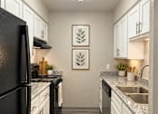 Thumbnail 12 of 14 - A kitchen with black appliances and white cabinets.