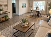 Thumbnail 11 of 14 - A living room with a coffee table in the center and a dining table in the background.