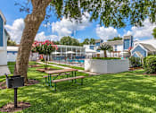 Thumbnail 1 of 14 - A tree with a mailbox stands in a grassy area with a picnic table and a pool in the background.