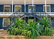 Thumbnail 9 of 14 - A blue house with a staircase and plants in front.