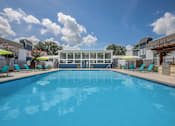 Thumbnail 7 of 14 - A large swimming pool with lounge chairs and umbrellas.
