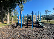 Thumbnail 6 of 14 - A playground with a blue slide and a green slide.