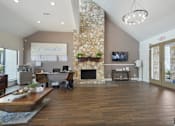 Thumbnail 1 of 15 - A living room with a stone fireplace and a flat screen TV mounted on the wall.