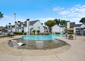 Thumbnail 2 of 15 - A pool surrounded by a stone patio and chairs.
