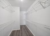 Thumbnail 15 of 15 - A walk in closet with white shelving and wood floors.