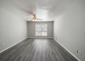 Thumbnail 10 of 15 - A room with a ceiling fan and wooden flooring.