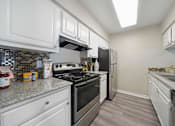 Thumbnail 4 of 15 - A kitchen with white cabinets and a stainless steel stove.