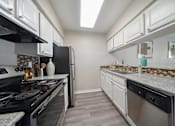 Thumbnail 3 of 15 - A kitchen with black appliances and white cabinets.
