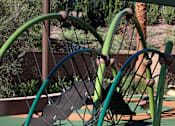 Thumbnail 40 of 45 - A playground with a green swing set and a brown bench.